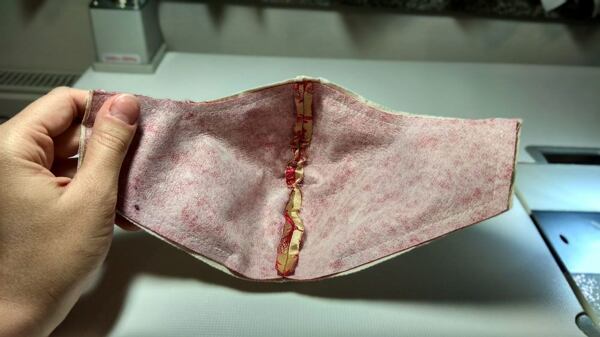 jak ušít roušku – ustřihněte rohy švových přídavků a nastřihněte několikrát v zakřivené části kolem nosu, otočte a vyžehlete